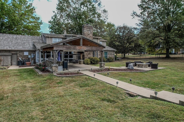 rear view of house with a patio, a fire pit, a yard, and a chimney