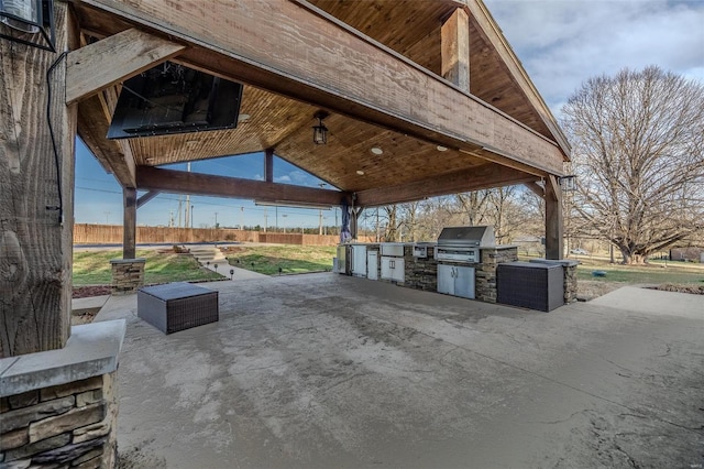 view of patio featuring an outdoor kitchen, grilling area, fence, and a gazebo