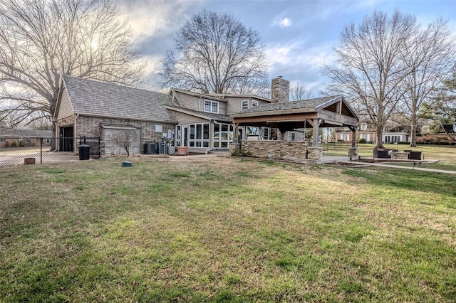 back of house featuring a chimney, a sunroom, cooling unit, brick siding, and a gazebo