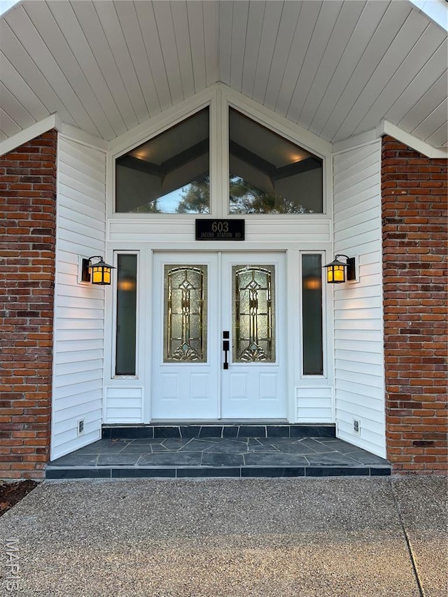 property entrance featuring brick siding and french doors