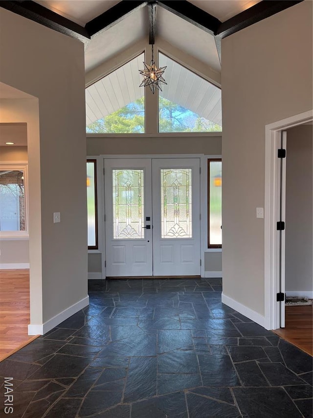 entryway featuring stone tile flooring, baseboards, and a chandelier