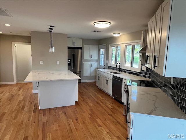 kitchen with high quality fridge, a sink, dishwasher, light wood finished floors, and light stone counters