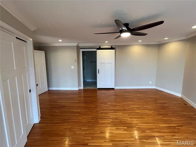 empty room with ornamental molding, a ceiling fan, wood finished floors, recessed lighting, and a barn door