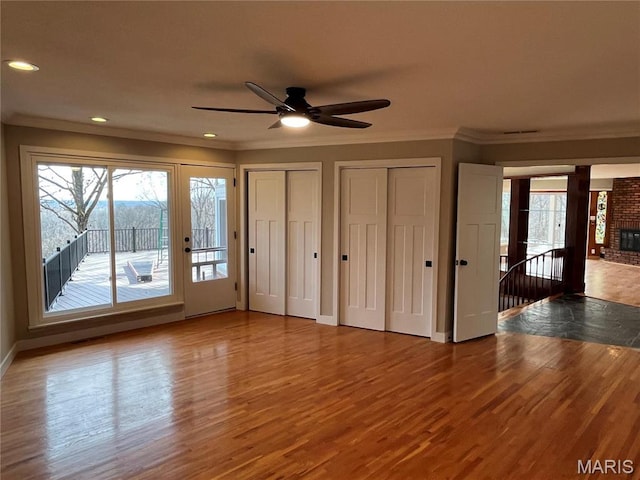 unfurnished bedroom featuring access to outside, ornamental molding, wood finished floors, two closets, and baseboards