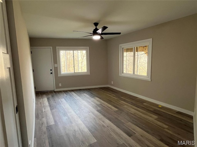 empty room with healthy amount of natural light, dark wood-style flooring, baseboards, and a ceiling fan