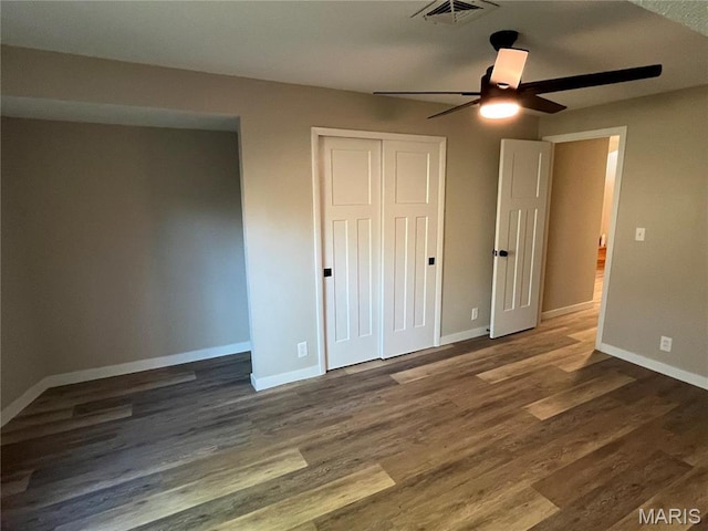 unfurnished bedroom with baseboards, wood finished floors, a closet, and a ceiling fan