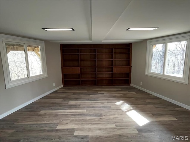 unfurnished bedroom featuring baseboards, wood finished floors, and multiple windows