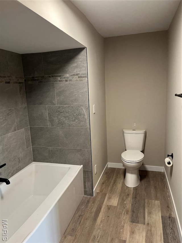 full bathroom featuring wood finished floors, toilet, a bath, and baseboards