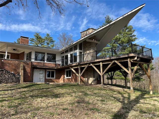 rear view of house featuring a chimney, a deck, a yard, and brick siding