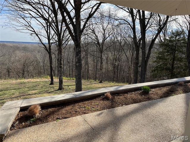 view of green lawn featuring a wooded view