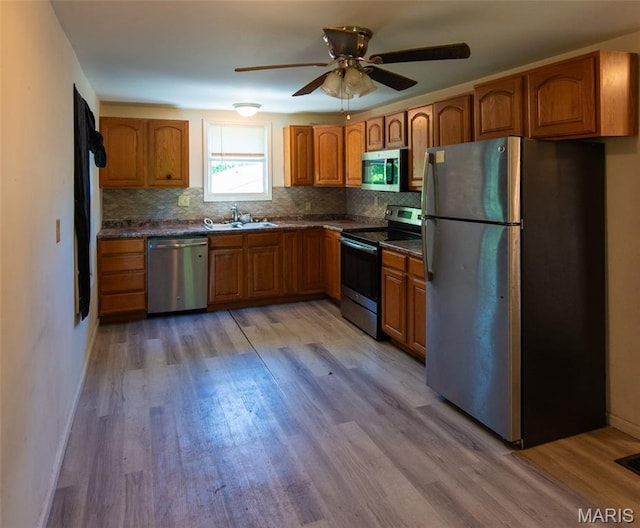 290 E Oak St, Saint Clair, MO 63077 - kitchen featuring stainless steel appliances, a sink, brown cabinets, dark countertops, and light wood-style floors