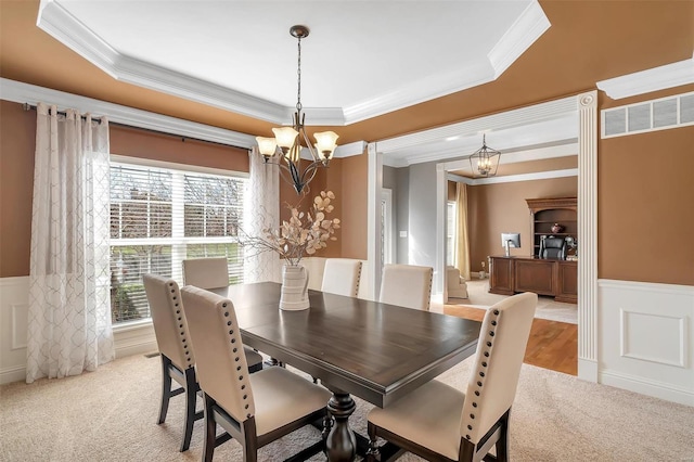 dining area with a chandelier, crown molding, wainscoting, light carpet, and a tray ceiling
