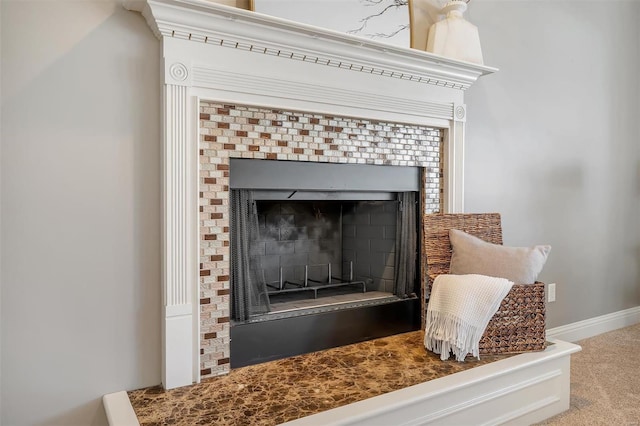 detailed view of a fireplace, baseboards, and carpet flooring