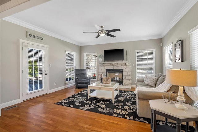 living room featuring a ceiling fan, crown molding, wood finished floors, a fireplace, and baseboards