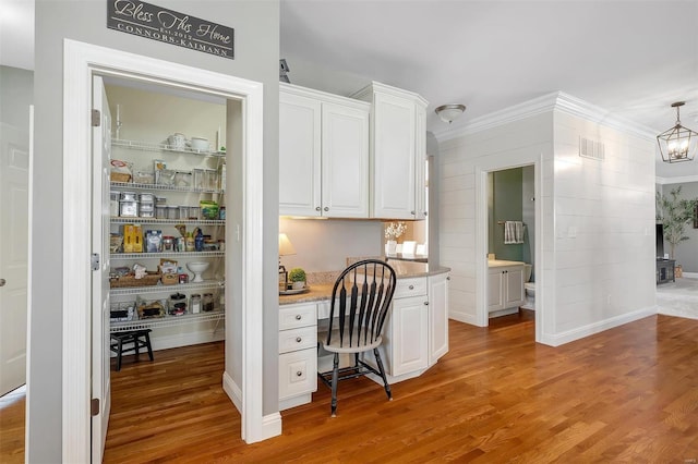 home office featuring light wood finished floors, built in study area, and crown molding