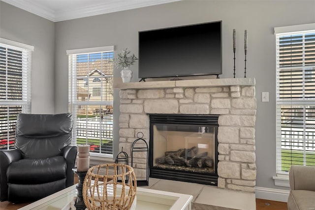 living area featuring crown molding, a fireplace, baseboards, and wood finished floors