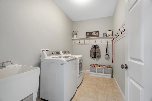 laundry area with separate washer and dryer, light tile patterned floors, and baseboards