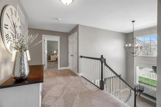 hallway with carpet, a chandelier, an upstairs landing, and baseboards