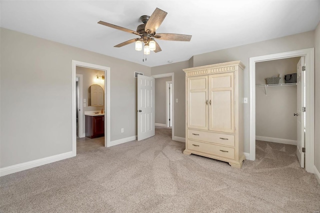 unfurnished bedroom featuring light colored carpet, a spacious closet, a closet, and baseboards