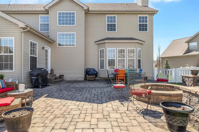 back of house featuring an outdoor fire pit, a patio, a chimney, and fence