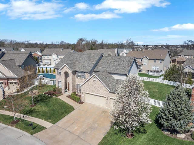 view of front of property featuring a residential view, concrete driveway, roof with shingles, and a garage