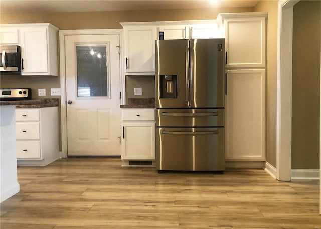kitchen featuring appliances with stainless steel finishes, white cabinets, light wood finished floors, and baseboards