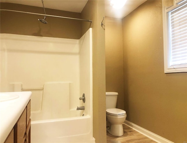 bathroom featuring toilet, wood finished floors, baseboards, vanity, and shower / bath combination