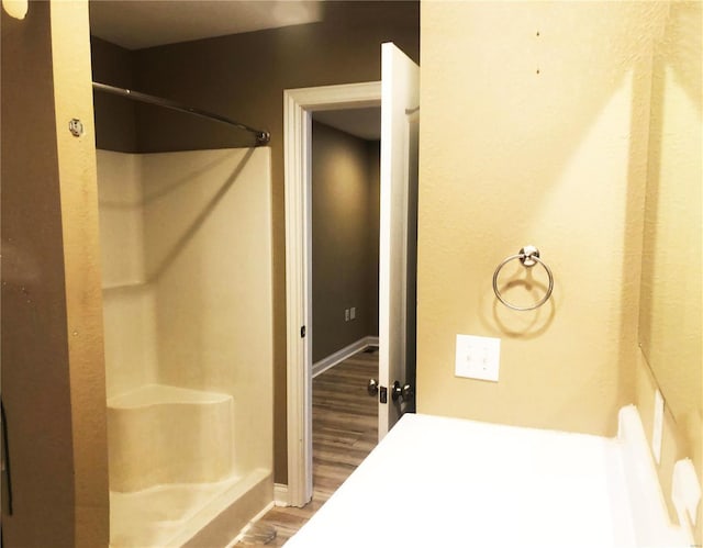 bathroom with wood finished floors, a shower, and baseboards