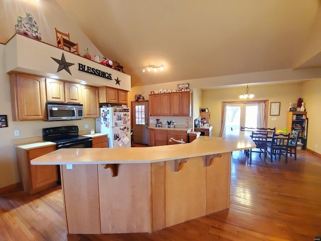 104 E Bryan St, Ewing, MO 63440 - kitchen with stainless steel microwave, black / electric stove, freestanding refrigerator, a kitchen breakfast bar, and light wood-style floors