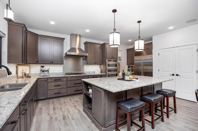 7121 Lost Oak Dr, Edwardsville, IL 62025 - kitchen featuring stainless steel appliances, wall chimney exhaust hood, a sink, dark brown cabinets, and a kitchen island