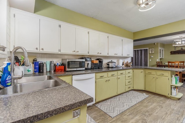 kitchen with stainless steel microwave, a peninsula, light wood-style floors, and backsplash