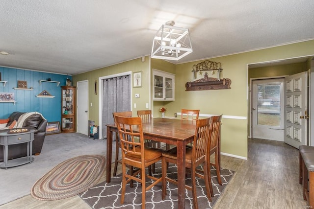 dining room with a textured ceiling, a chandelier, and wood finished floors