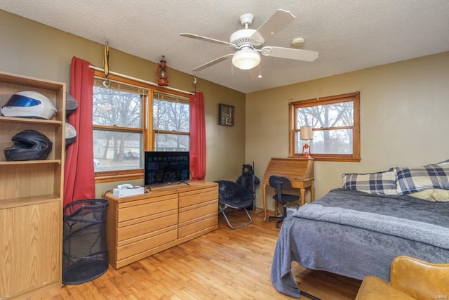 bedroom with light wood-type flooring, a textured ceiling, and ceiling fan
