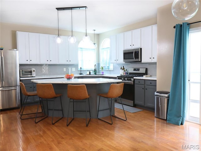 6804 Laurel Springs Ct, Fairview Heights, IL 62208 - kitchen with appliances with stainless steel finishes, a center island, tasteful backsplash, and light wood-style flooring