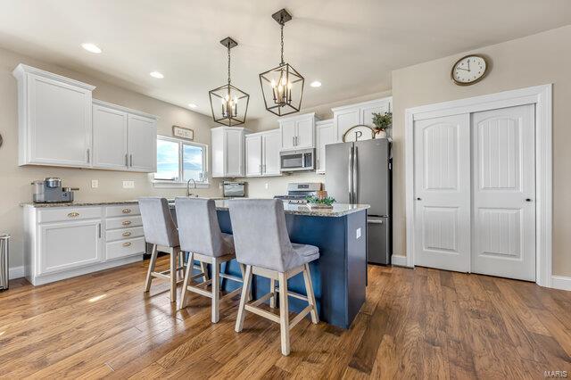 620 Lubbuck Ct, Moscow Mills, MO 63362 - kitchen featuring stainless steel appliances, white cabinets, a kitchen island, a chandelier, and a breakfast bar