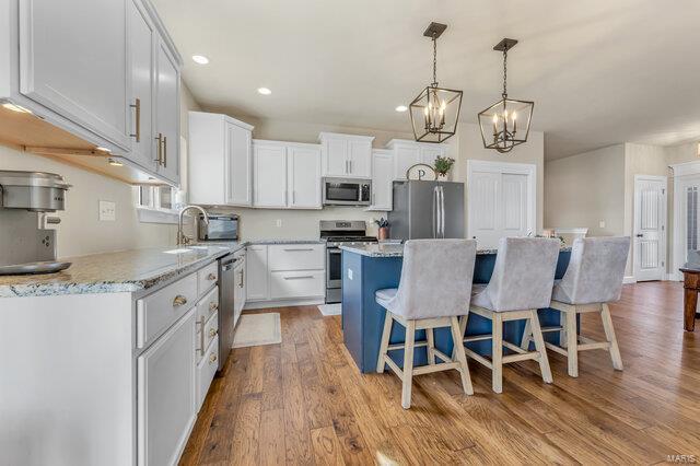 620 Lubbuck Ct, Moscow Mills, MO 63362 - kitchen with appliances with stainless steel finishes, a sink, a kitchen island, a chandelier, and wood finished floors