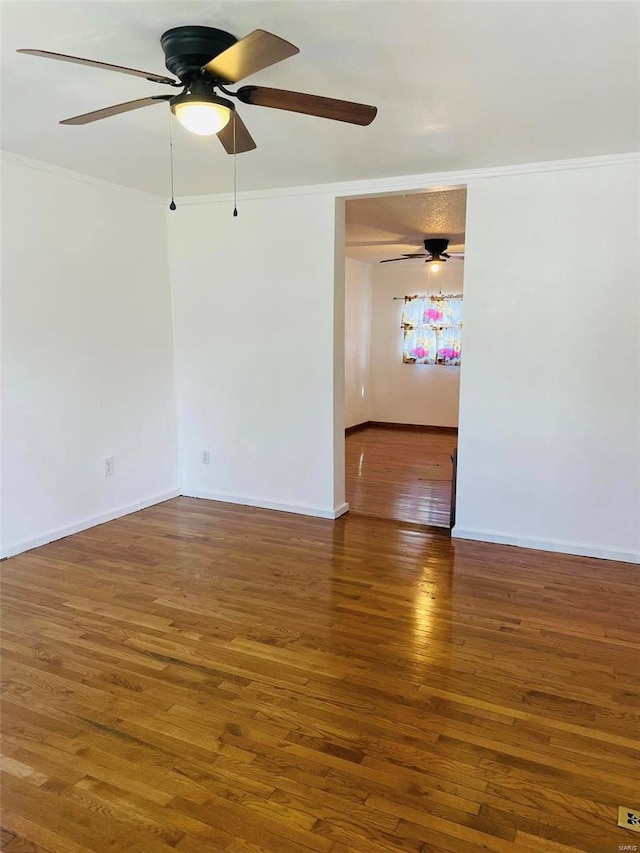 unfurnished room featuring crown molding, wood finished floors, ceiling fan, and baseboards