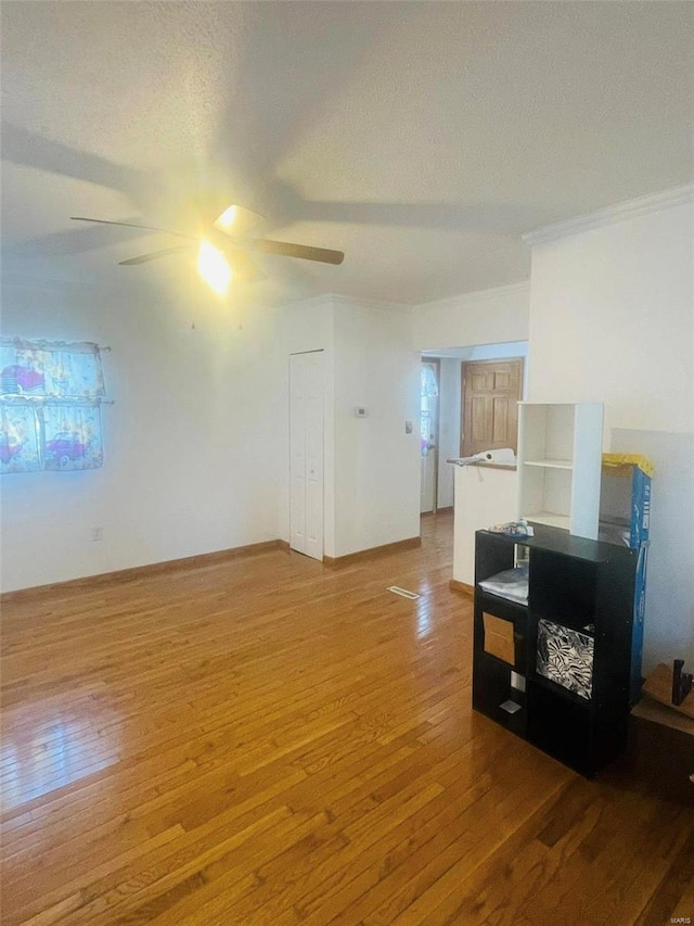 unfurnished room featuring light wood-type flooring, a ceiling fan, a textured ceiling, and crown molding