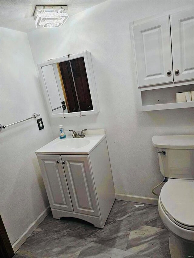 half bathroom featuring baseboards, toilet, and vanity