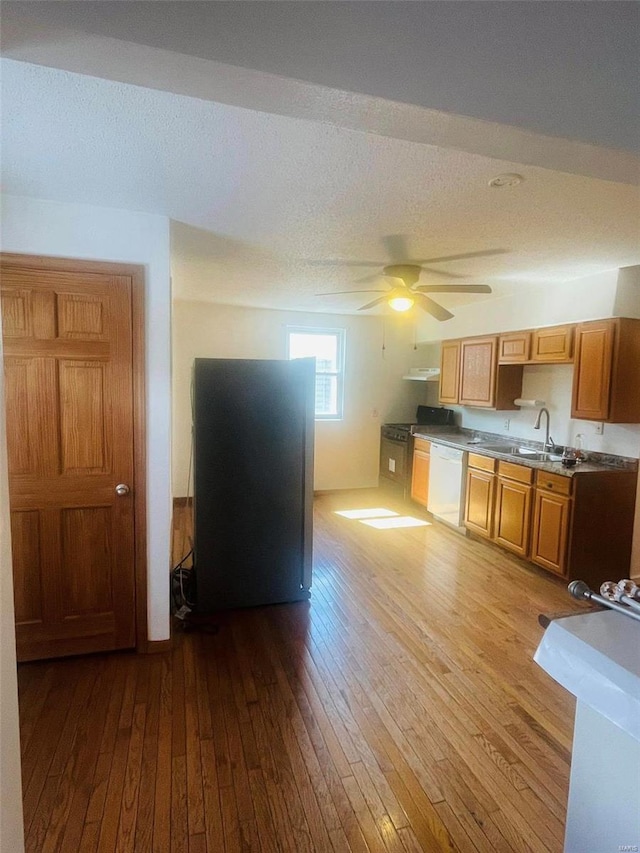kitchen with white dishwasher, wood-type flooring, a sink, a ceiling fan, and a textured ceiling