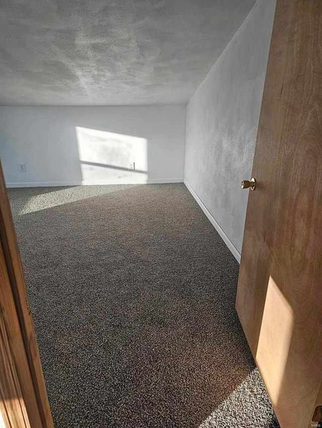 carpeted empty room featuring baseboards