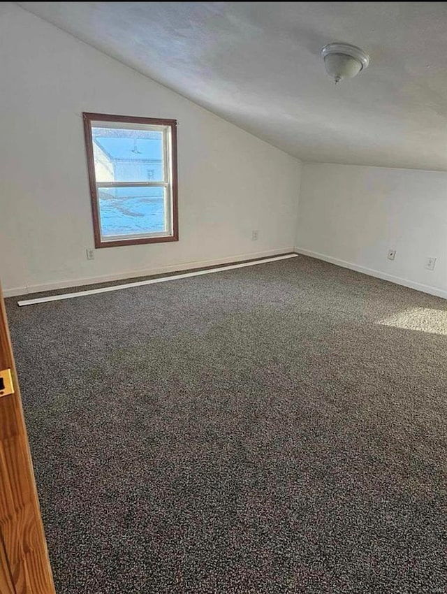 unfurnished room featuring vaulted ceiling, carpet, and baseboards