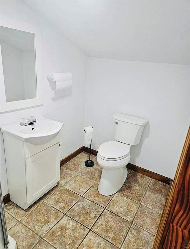 bathroom featuring vanity, baseboards, toilet, and vaulted ceiling