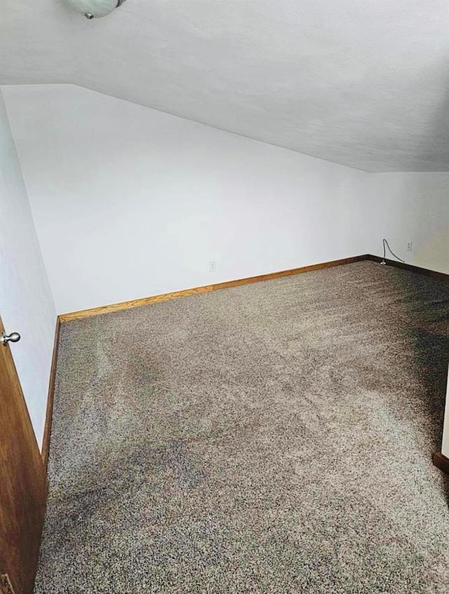 additional living space featuring carpet flooring, vaulted ceiling, and baseboards
