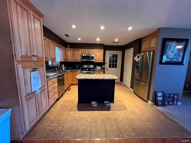 kitchen featuring appliances with stainless steel finishes, a kitchen island, light tile patterned floors, and recessed lighting