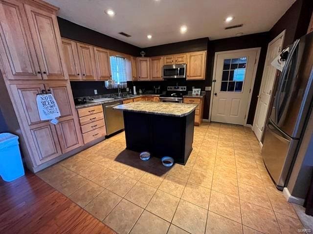 kitchen featuring stainless steel appliances, a center island, a sink, recessed lighting, and light stone countertops