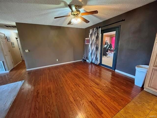 empty room featuring ceiling fan, a textured ceiling, wood finished floors, and baseboards