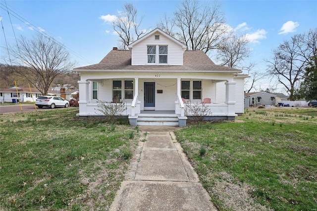 bungalow-style home with a porch, a front lawn, and roof with shingles