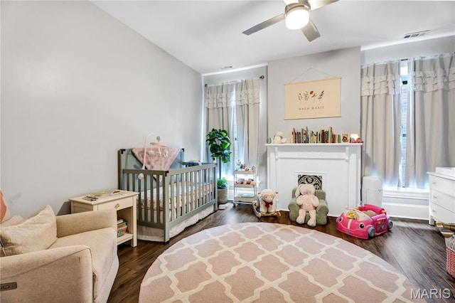 4716 Olive St, Saint Louis, MO 63108 - bedroom with multiple windows, a crib, wood finished floors, and ceiling fan