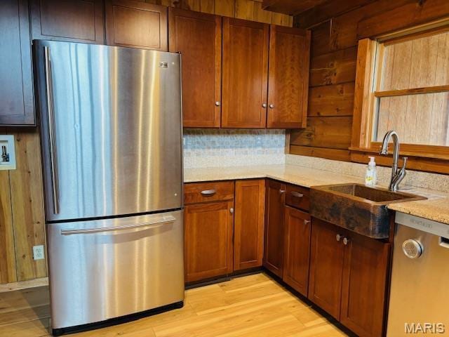 19125 County Road 1220, St James, MO 65559 - kitchen featuring appliances with stainless steel finishes, light wood-style flooring, a sink, wood walls, and decorative backsplash
